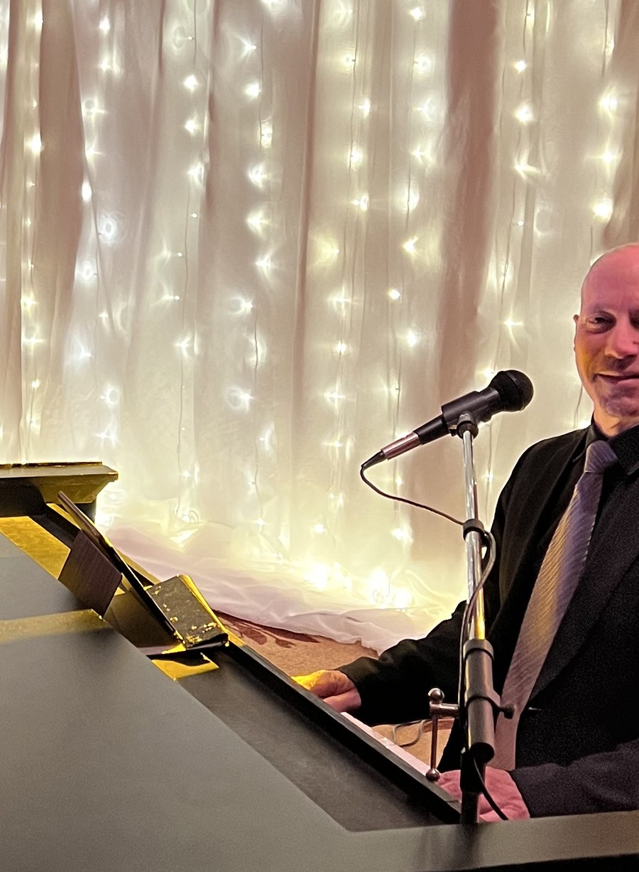 Joel Nelson performing at a grand piano at a dueling-pianos event
