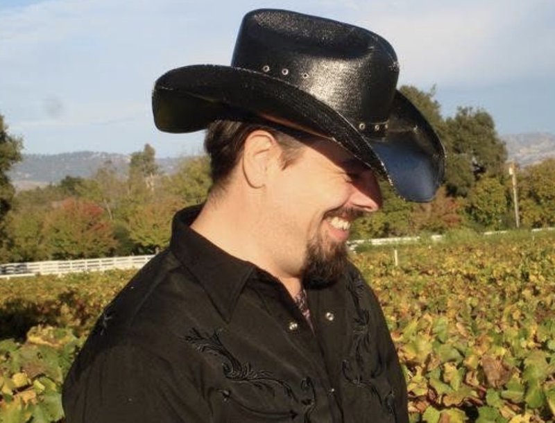 Michael Roy Gutierrez smiling outdoors in a vineyard setting